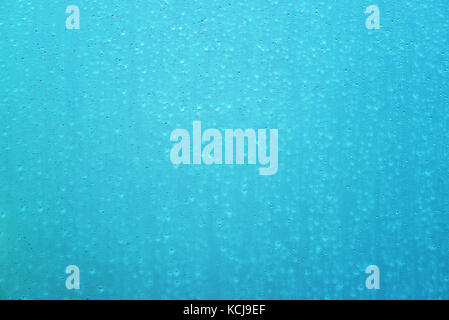Vetro bagnato come superficie astratta moderna teal sfondo. gocce d'acqua sulla finestra pulita. gocce di pioggia nella stagione delle piogge la formazione di pattern unici. Foto Stock