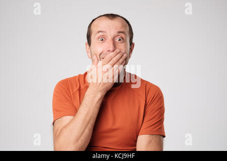 Coppia uomo caucasico in t-shirt la chiusura di una bocca con le mani su uno sfondo luminoso. Foto Stock