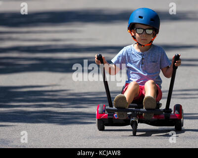 Felice ragazzo in piedi su hoverboard o gyroscooter con kart kit di accessori outdoor. nuove tecnologie moderne Foto Stock