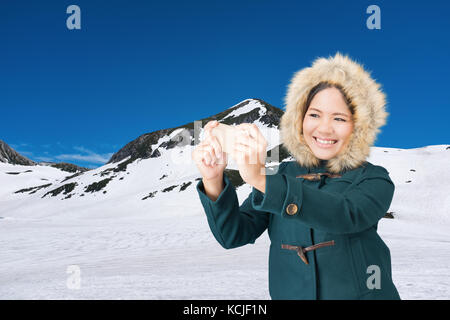Donna asiatica che indossa manto verde con cappello di pelliccia sulla montagna di neve Foto Stock