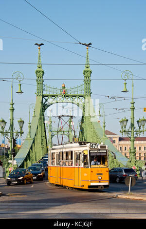 Il ganz csmg il tram a budapest attraversando il ponte della libertà in una giornata di sole con cielo blu. Foto Stock