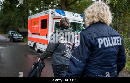 Ochtrup, Germania. 6th Ott 2017. Un attivista che si oppone all'enegry nucleare è scortato in un'automobile dell'ambulanza da un ufficiale di polizia vicino a Ochtrup, Germania, 6 ottobre 2017. Vicino a Gronau, nella regione di Muensterland, gli attivisti hanno bloccato i binari del treno per oltre undici ore. Volevano fermare un treno che raggiungesse l'impianto di trasformazione dell'uranio di Gronau. Il percorso è stato chiuso fino alle prime ore del mattino. Credit: Guido Kirchner/dpa/Alamy Live News Foto Stock