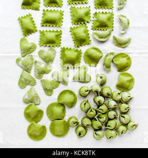 Vari mix di fresco ravioli fatti in casa. raccolta di tortellini verde su bianco. ravioli e tortellini, ravioli, gnocchi, cuore Foto Stock