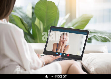 Ragazza casual parla a ridere ragazza tramite video conferenza applicazione. donna fa appello a femmina amico su laptop. distanza lunga amicizia, virt Foto Stock