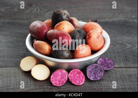 Freschi patate colorate nel recipiente di metallo sul tavolo di legno Foto Stock