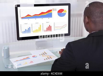 Vista posteriore di un imprenditore analizzando il grafico su computer Foto Stock