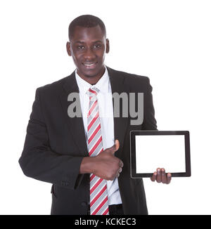 Ritratto di felice giovane imprenditore africano puntando sulla tavoletta digitale Foto Stock