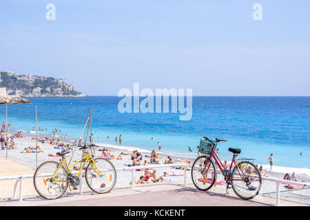 Nice cote d'Azur, Francia - giugno 27,2017: bella vista diurna a città mare blu. la gente camminare e rilassarsi sulla spiaggia. due biciclette parcheggiate sul suolo Foto Stock