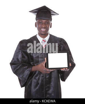 Uomo felice in veste di graduazione azienda vuoto vuoto Tablet Pc su sfondo bianco Foto Stock