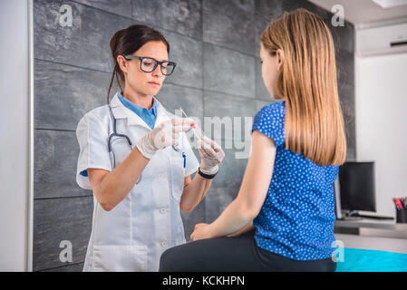 Pediatra femmina usando un bastoncino di cotone per prelevare un campione da un paziente la gola Foto Stock