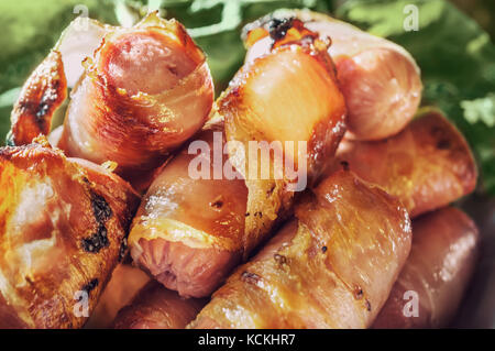 Salsicce avvolto in pancetta grigliate sul barbecue. Close-up. Messa a fuoco selettiva. Foto Stock