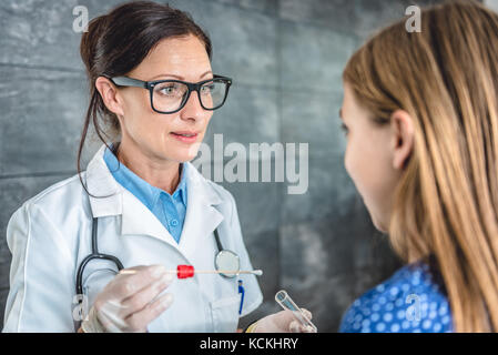 Pediatra femmina usando un bastoncino di cotone per prelevare un campione da un paziente la gola Foto Stock