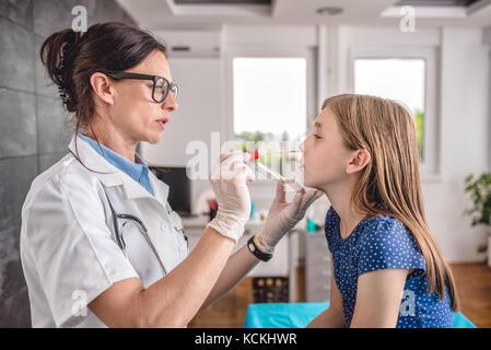 Pediatra femmina usando un bastoncino di cotone per prelevare un campione da un paziente la gola Foto Stock