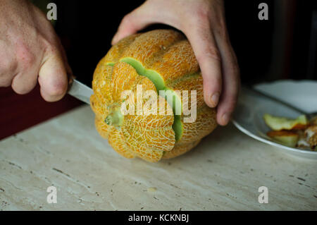 Insolito halloween melone, processo di taglio, le sementi e gli avanzi sul tavolo della cucina. Foto Stock