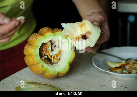 Insolito halloween melone, processo di taglio, le sementi e gli avanzi sul tavolo della cucina. Foto Stock