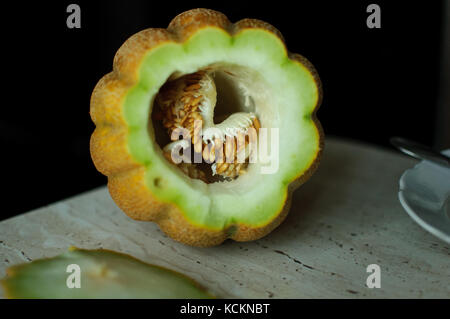 Insolito halloween melone, processo di taglio, le sementi e gli avanzi sul tavolo della cucina. Foto Stock