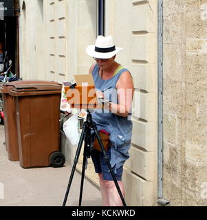 Artista femminile pittura di una scena di strada in francese languedoc città di pezenas, HERAULT, Francia Foto Stock