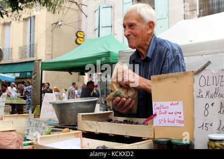 Anziani ma allegro senior uomo al lavoro su un mercato di vendita di stallo olive e conserva in strada nel languedoc città di pezenas, HERAULT, Francia Foto Stock