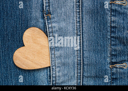 In legno marrone cuore nella tasca dei jeans blu della giacca Texture di sfondo Copyspace. Foto Stock