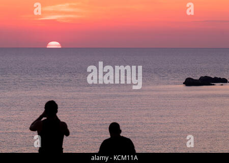 Coppia giovane stagliano guardare un bel tramonto d'oro Foto Stock