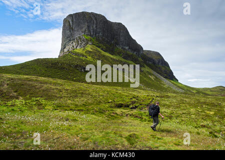 Un camminatore sotto il naso di un Sgùrr, o lo Sgurr di Eigg, sull'isola di Eigg, Scozia, Regno Unito Foto Stock