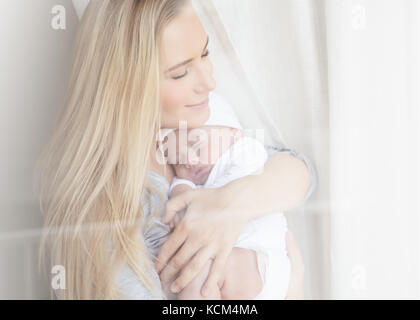 Ritratto di una bella madre con gli occhi chiusi di piacere holding adorabili neonato Bambino dormiente, felice maternità concept Foto Stock