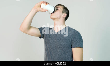 Giovane uomo di bere il caffè usa e getta dal bicchiere di carta su sfondo bianco Foto Stock