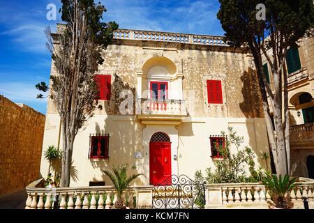 Casa cittadina con un rosso serramenti in Bastion Square, Mdina, Malta, l'Europa. Foto Stock
