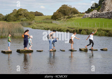 Le famiglie che attraversa un fiume su pietre miliari Foto Stock