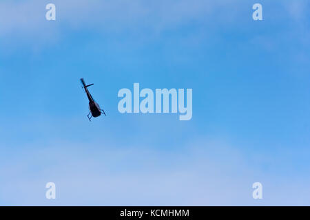 Un elicottero che vola attraverso il cielo blu con nuvole morbido Foto Stock