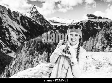 Inverno sul livello superiore di divertimento. ritratto di felice giovane donna turistica nella parte anteriore del paesaggio di montagna in alto adige, italia con foto d'epoca camer Foto Stock