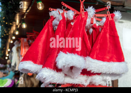 Red santa clausola hat appeso in un mercato in fase di stallo. Foto Stock