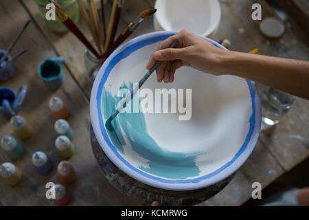 Potter femmina pittura a mano una ciotola in negozio di ceramiche Foto Stock