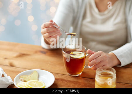 Ravvicinata di una donna malata bere il tè con il limone Foto Stock