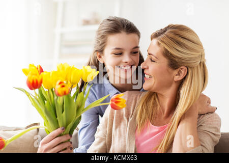 Felice ragazza dando ai fiori di madre a casa Foto Stock