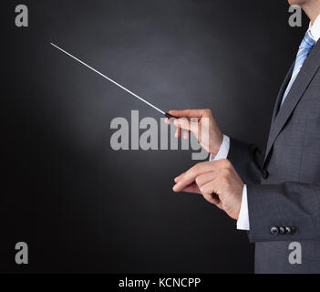 Close-up di Direttore di Orchestra Mani Baton su sfondo nero Foto Stock