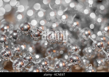 Abstract argento sfondo di Natale. filettatura con perle con riflessi dorati e bellissimo bokeh di fondo. Foto Stock