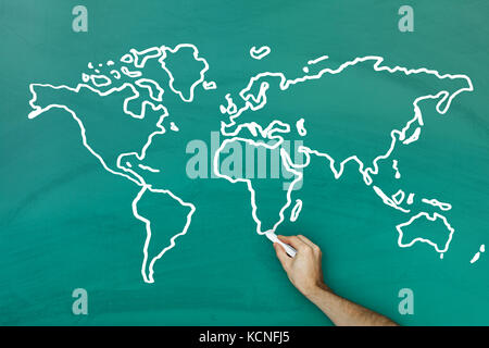 Mano azienda chalk disegno mappa del mondo sulla lavagna Foto Stock
