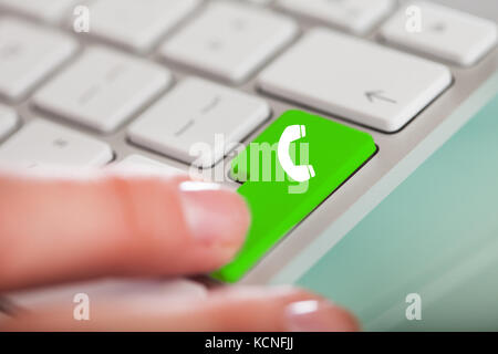 Close-up di mano spingendo il blu Contattaci pulsante sulla tastiera bianca Foto Stock
