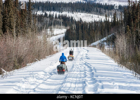 Due snowmobiliers fanno la loro strada lungo il canol Heritage Trail, circa 100 km a nord-est del fiume Ross, Yukon Territory, Canada Foto Stock