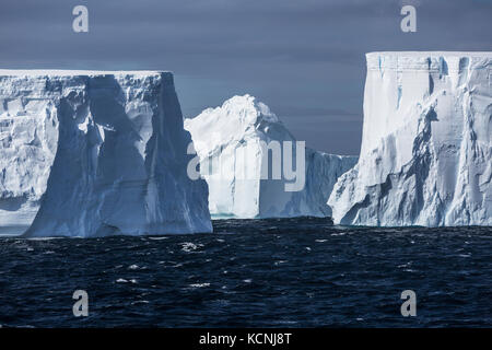 Grandi iceberg tabulari lentamente galleggiante da sul vento spazzata di acque del suono antartico, penisola antartica Foto Stock