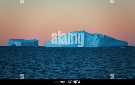 Twilight trova iceberg galleggianti in acqua contro un arancio cielo privo di nuvole vicino fournier bay, penisola antartica Foto Stock