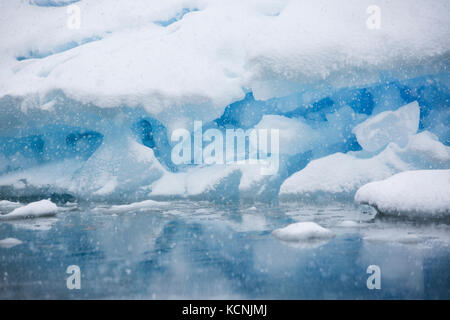 La neve cade su un iceberg a terra vicino a pleneau island con le sue tante sfumature di blu dà l impressione di essere dentro una snowglobe, pleneau island, penisola antartica Foto Stock