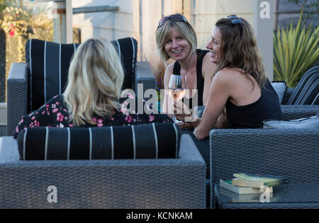 Tre amiche rilassati in un patio esterno mentre visitano il Kingfisher resort e spa. Il Comox Valley, l'isola di Vancouver, British Columbia, Canada. Foto Stock