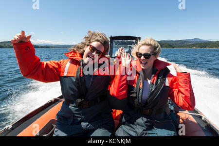 Due amici ti guatterono per un'escursione di avvistamento delle balene dal lato anteriore del loro zodiak, appena a sud di Seymour Narrows. Campbell River, Vancouver Island, British Columbia, Canada. Foto Stock