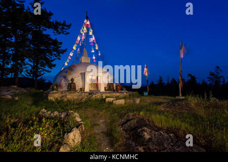 Uno stupa buddisti con la preghiera bandiere al vento sono accese fino a notte in un rifugio su cortes Island, isola di Cortes, British Columbia, Canada Foto Stock