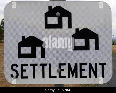 Un segno in outback australia consulenza di un insediamento di case lungo la strada Foto Stock