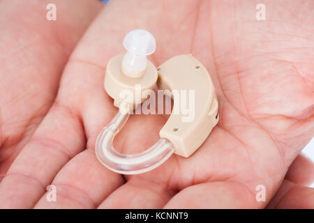 Close-up di mano d'uomo azienda Hearing Aid Foto Stock