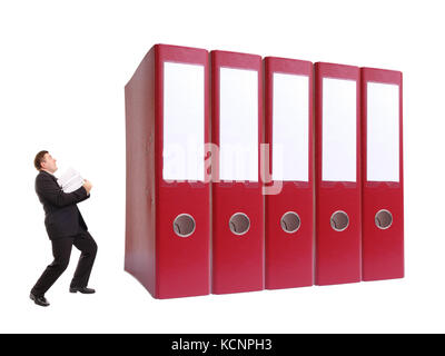 Imprenditore in abito nero tenendo una pila di documenti in piedi nella parte anteriore della fila di gigante raccoglitori ad anello su sfondo bianco Foto Stock