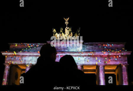 Berlino, Germania. 6 ottobre 2017. I visitatori osservano la porta di Brandeburgo illuminata durante il Festival delle luci di Berlino, capitale della Germania, il 6 ottobre 2017. Berlino è diventata una città di arte leggera con l'apertura del Festival delle luci il venerdì, che durerà dal 6 al 15 ottobre. Crediti: Shan Yuqi/Xinhua/Alamy Live News Foto Stock